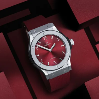 the Hublot Classic Fusion Titanium Seddiqi 75th Anniversary watch with its distinctive burgundy dial and Eastern Arabic numerals, set against a dark, geometric backdrop