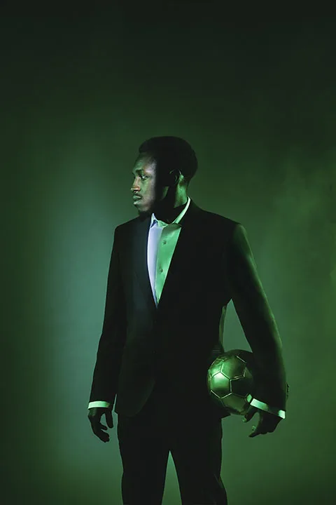 Saudi footballer Saud Abdulhamid wearing a suit and holding a football