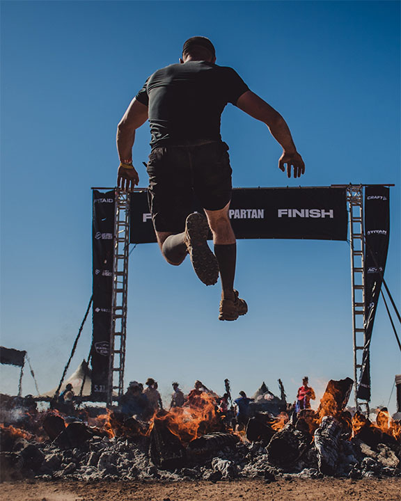a man jumping over fire during the Spartan Race Middle East Dubai Abu Dhabi